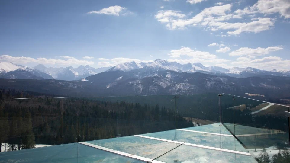 Taras ze szklaną podłogą i balustradą z widokiem na góry