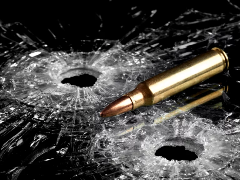 Nabój leżący na szkle z dwiema dziurami po kulach